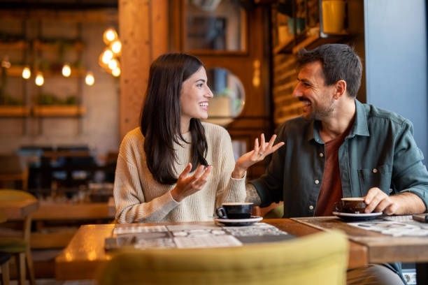 Ett par samtalar leende över kaffe på ett café